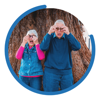 Older couple in a park with acorns over their eyes.